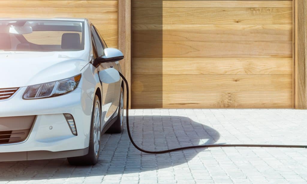 A white electric car is charged at a ev charger.