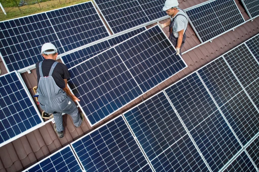 Zwei Techniker bei der Installation einer Solaranlage auf einem Hausdach.