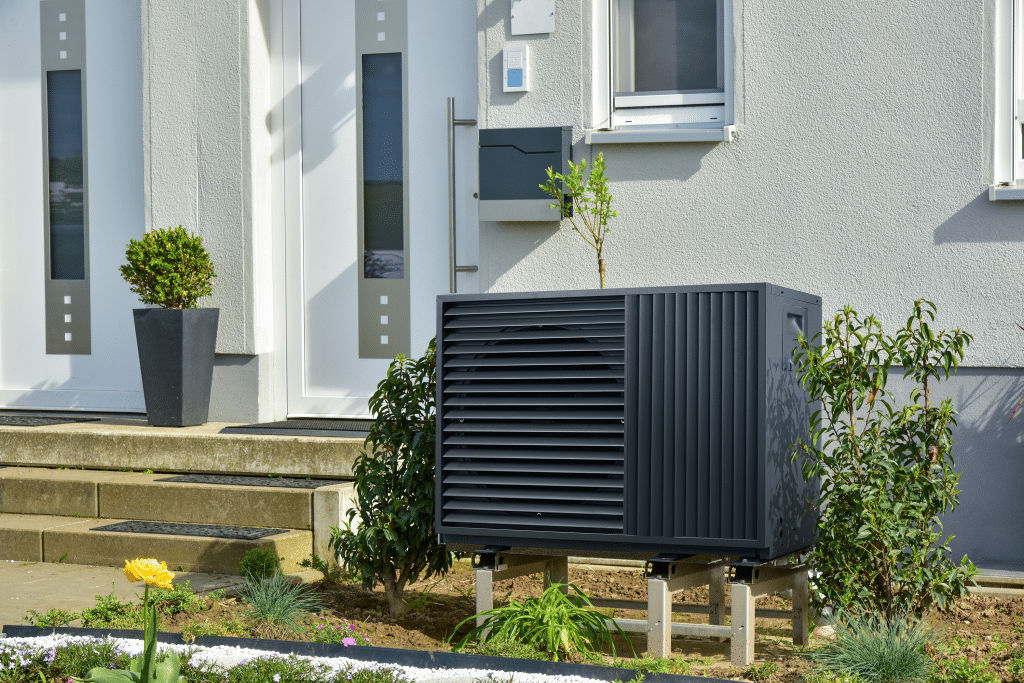 A black heat pump in front of the façade of a private home.