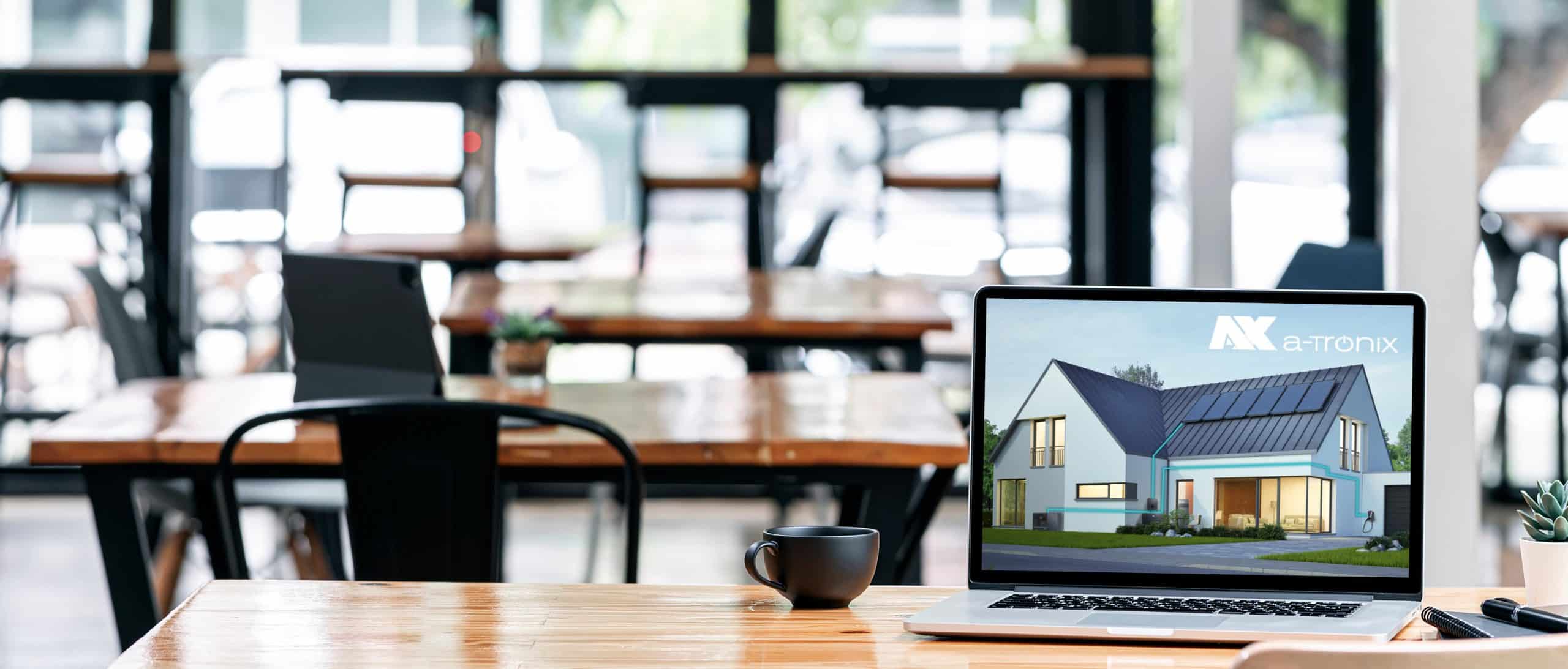 The official website of the a-TroniX brand is displayed on the screen of a laptop on a café table.